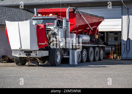 Semi-camion à benne basculante grand engin de forage rouge de qualité industrielle avec capot ouvert avec un moteur cassé debout avec des pièces de rechange démontées sur le parking près d'un Banque D'Images