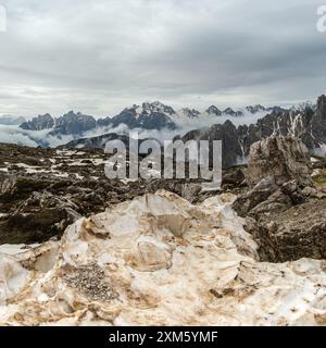 Dolomites en juin : randonnée Tre Cime circuit avec des sentiers enneigés et des sommets entourés de nuages Banque D'Images