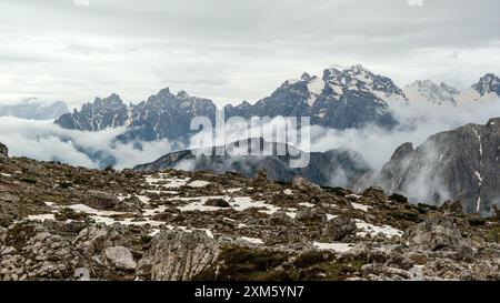 Circuit Tre Cime : sentiers enneigés et sommets des Dolomites émergeant à travers la brume brumeuse de juin Banque D'Images