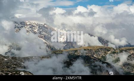 Circuit Tre Cime de juin : sentiers enneigés et sommets des Dolomites émergeant à travers le brouillard imprévisible Banque D'Images