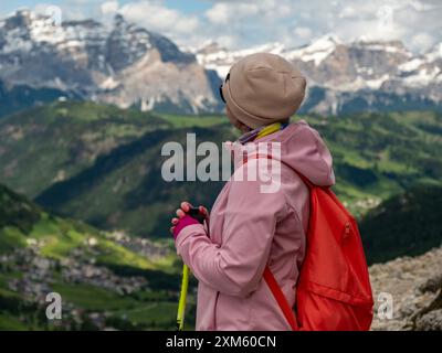 Embrassez la tranquillité des Dolomites tandis que cette femme regarde sur le magnifique col de Gardena, où le paysage de montagne à couper le souffle se déploie Banque D'Images