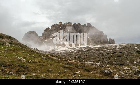 Randonnée Tre Cime circuit en juin : paysage enneigé et brouillard enveloppant les impressionnants sommets des Dolomites. Banque D'Images