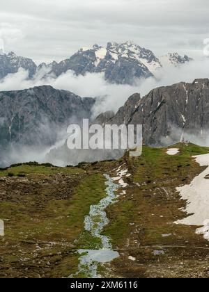 Circuit tre Cime en juin : neige et nuages créent une scène enchanteresse avec les sommets des Dolomites Banque D'Images