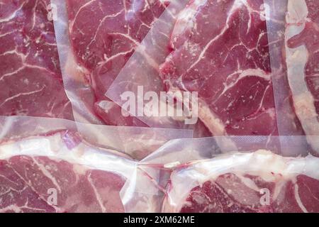 Gros plan de bœuf biologique (osso buco) dans un emballage scellé sous vide avec fond blanc Banque D'Images