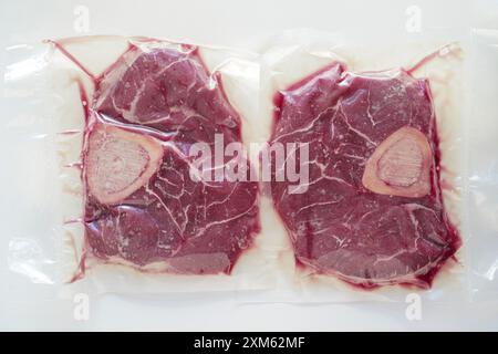 Gros plan de bœuf biologique (osso buco) dans un emballage scellé sous vide avec fond blanc Banque D'Images