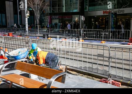 Sydney, Australie, le conseil commercial des gens qui posent un nouveau sentier le long de George Street dans le centre-ville, travaillant à genoux pour poser des dalles Banque D'Images