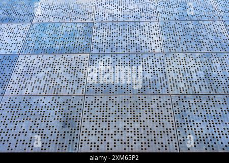 Vue de haut en bas d'un mur métallique perforé texturé présentant un motif complexe et capturant l'interaction de la lumière et de l'ombre sur un architecte moderne Banque D'Images