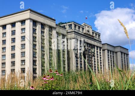 Bâtiment du parlement russe à Moscou, vue à travers des fleurs à la façade de la Douma d'État de Russie avec drapeau Banque D'Images