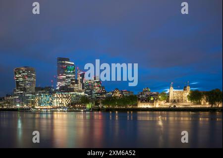La Tour de Londres, avec les gratte-ciel de la City de Londres derrière elle. Illuminé la nuit. Banque D'Images