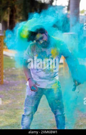 Un jeune homme couvert de poudre colorée lors d'une célébration du festival Holi en plein air. Banque D'Images