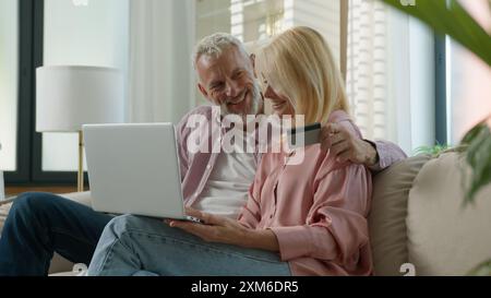 Heureux mature souriant senior couple caucasien vieux grands-parents de famille femme homme femme masculin utiliser l'ordinateur portable de carte de crédit pour les achats en ligne de facture de paiement Banque D'Images