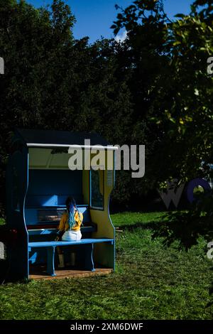 Ambiance pendant Womad - World of Music, Arts and Dance 2024 le vendredi 26 juillet 2024 au Charlton Park, Malmesbury. Une jeune femme jouant un des nombreux instruments de musique placés autour du festival. Photo de Julie Edwards. Banque D'Images