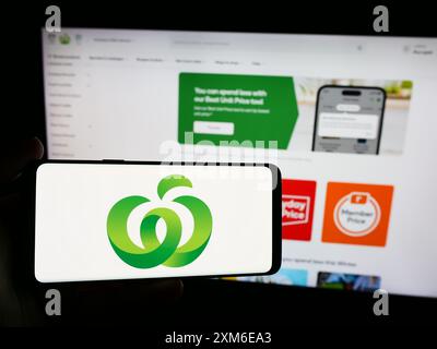 Personne tenant un smartphone avec le logo de la chaîne australienne Woolworths supermarchés en face du site Web. Concentrez-vous sur l'affichage du téléphone. Banque D'Images