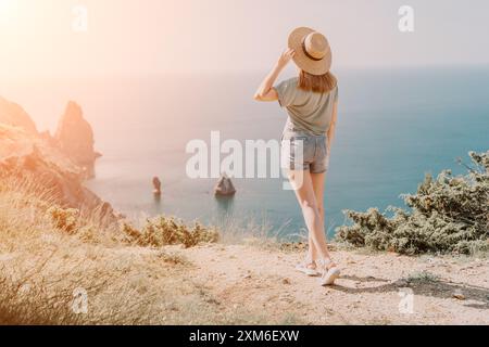Jeune femme au chapeau admirant une vue côtière Banque D'Images