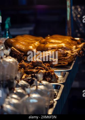 Canard rôti exposé à un marché nocturne, prêt à la vente. Banque D'Images