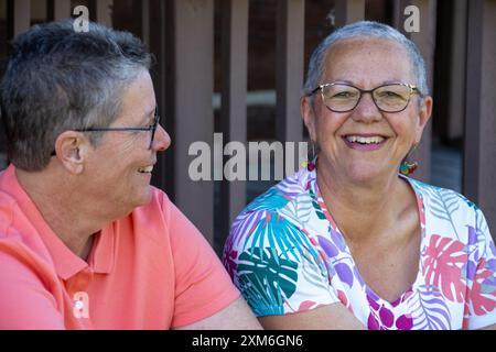 Couple gay plus âgé assis et souriant ensemble à l'extérieur Banque D'Images
