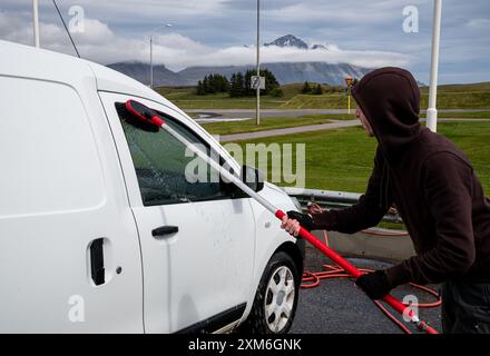 Homme lavant sa voiture avec un jet d'eau à haute pression en Islande. Banque D'Images