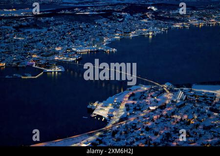 Vue aérienne du paysage urbain de Tromso la nuit en hiver avec des bâtiments enneigés et des rues illuminées. Banque D'Images