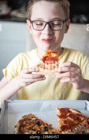 Joli adolescent mangeant de la pizza dans la boîte à emporter Banque D'Images