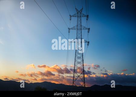 pylône d'électricité à haute tension également connu sous le nom de tour de puissance ou de tour de transmission électrique silhouettée contre un ciel présentant une belle palette de Banque D'Images