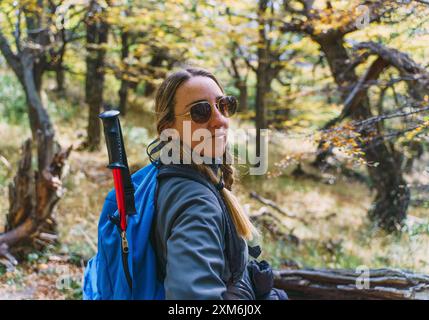 Une femme portant des lunettes de soleil sur une bûche dans une forêt Banque D'Images