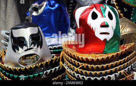 Photo en gros plan de masques de lutte assis dans des piles de chapeaux mexicains « sombreros » Banque D'Images