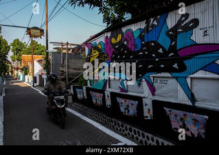 26 juillet 2024, Yogyakarta, région spéciale de Yogyakarta, Indonésie : un motocycliste passe devant une murale sur le thème des OVNIS et des extraterrestres dans le village des OVNIS dans le district de Mantrijeron, ville de Yogyakarta. Les résidents ont collaboré pour décorer le village avec un thème OVNI et extraterrestre pour accueillir le jour de l'indépendance de la République d'Indonésie le 17 août. En outre, le village OVNI est conçu comme un langage pour étudier l'univers, de sorte que les gens sont toujours conscients de maintenir la propreté dans leurs environnements respectifs. (Crédit image : © Angga Budhiyanto/ZUMA Press Wire/Alamy Live News) USAGE ÉDITORIAL SEULEMENT! Banque D'Images