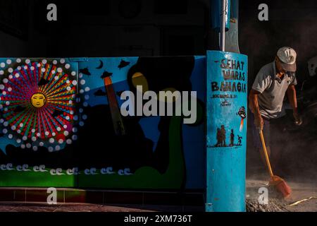 26 juillet 2024, Yogyakarta, région spéciale de Yogyakarta, Indonésie : un homme balaye près d'une murale avec un thème OVNI et extraterrestre dans le village d'OVNIS dans le district de Mantrijeron, ville de Yogyakarta. Les résidents ont collaboré pour décorer le village avec un thème OVNI et extraterrestre pour accueillir le jour de l'indépendance de la République d'Indonésie le 17 août. En outre, le village OVNI est conçu comme un langage pour étudier l'univers, de sorte que les gens sont toujours conscients de maintenir la propreté dans leurs environnements respectifs. (Crédit image : © Angga Budhiyanto/ZUMA Press Wire/Alamy Live News) USAGE ÉDITORIAL SEULEMENT! Non f Banque D'Images