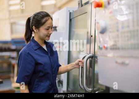 Jeunes femmes travailleuses d'ingénieur technicien travaillant avec la machine à métaux de tour CNC dans l'usine moderne de l'industrie sidérurgique Banque D'Images