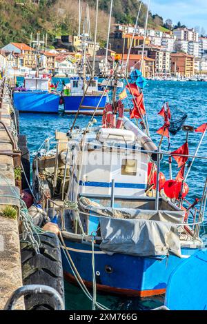 Scène portuaire avec un groupe de bateaux amarrés colorés, doucement tournoyant sur l'eau calme. Banque D'Images