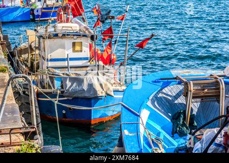 Scène portuaire avec un groupe de bateaux amarrés colorés, doucement tournoyant sur l'eau calme. Banque D'Images