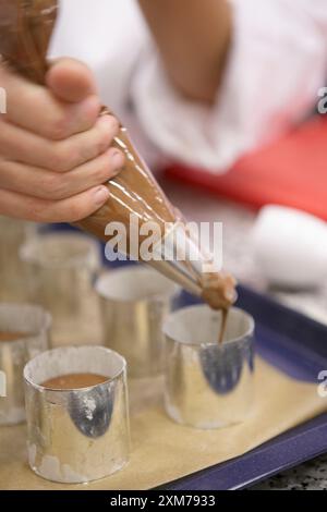 Versez la mousse au chocolat dans les anneaux à dessert Banque D'Images
