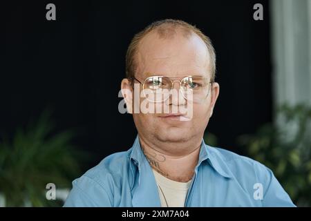 Un homme inclusif avec des lunettes regarde directement la caméra avec une expression focalisée. Banque D'Images