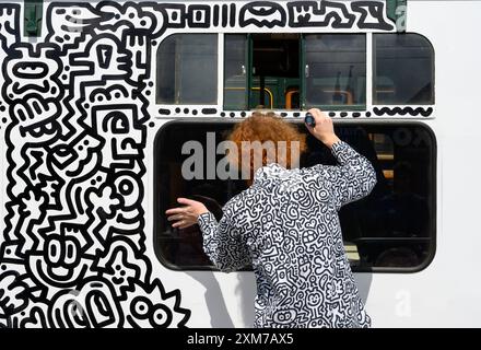 Tenterden, Kent, Royaume-Uni. 26 juillet 2024. L'artiste de renommée internationale Mr Doodle (Sam Cox) crée le premier train Doodle au monde, couvrant un wagon de 64 pieds avec ses griffes signature - pour marquer le 50e anniversaire du chemin de fer Kent et East Sussex, à sa base à la gare de Tenterden dans sa ville natale. Crédit : Phil Robinson/Alamy Live News Banque D'Images