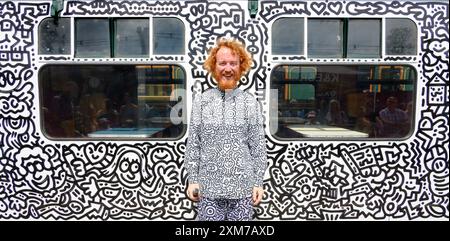 Tenterden, Kent, Royaume-Uni. 26 juillet 2024. L'artiste de renommée internationale Mr Doodle (Sam Cox) crée le premier train Doodle au monde, couvrant un wagon de 64 pieds avec ses griffes signature - pour marquer le 50e anniversaire du chemin de fer Kent et East Sussex, à sa base à la gare de Tenterden dans sa ville natale. Crédit : Phil Robinson/Alamy Live News Banque D'Images