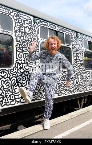 Tenterden, Kent, Royaume-Uni. 26 juillet 2024. L'artiste de renommée internationale Mr Doodle (Sam Cox) crée le premier train Doodle au monde, couvrant un wagon de 64 pieds avec ses griffes signature - pour marquer le 50e anniversaire du chemin de fer Kent et East Sussex, à sa base à la gare de Tenterden dans sa ville natale. Crédit : Phil Robinson/Alamy Live News Banque D'Images