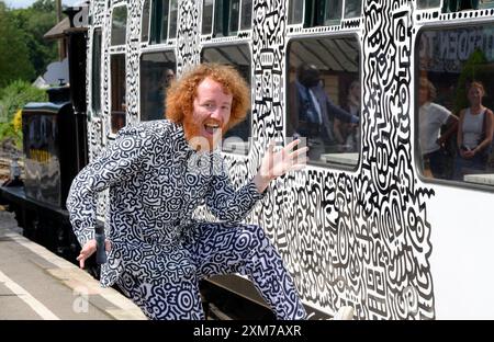 Tenterden, Kent, Royaume-Uni. 26 juillet 2024. L'artiste de renommée internationale Mr Doodle (Sam Cox) crée le premier train Doodle au monde, couvrant un wagon de 64 pieds avec ses griffes signature - pour marquer le 50e anniversaire du chemin de fer Kent et East Sussex, à sa base à la gare de Tenterden dans sa ville natale. Crédit : Phil Robinson/Alamy Live News Banque D'Images