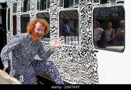 Tenterden, Kent, Royaume-Uni. 26 juillet 2024. L'artiste de renommée internationale Mr Doodle (Sam Cox) crée le premier train Doodle au monde, couvrant un wagon de 64 pieds avec ses griffes signature - pour marquer le 50e anniversaire du chemin de fer Kent et East Sussex, à sa base à la gare de Tenterden dans sa ville natale. Crédit : Phil Robinson/Alamy Live News Banque D'Images