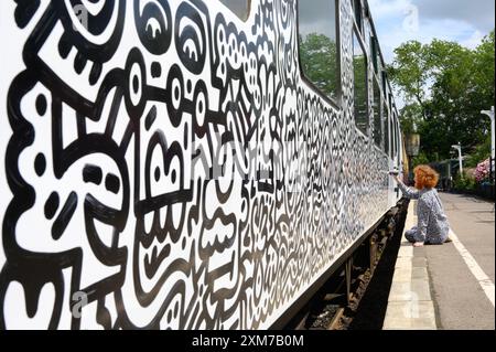 Tenterden, Kent, Royaume-Uni. 26 juillet 2024. L'artiste de renommée internationale Mr Doodle (Sam Cox) crée le premier train Doodle au monde, couvrant un wagon de 64 pieds avec ses griffes signature - pour marquer le 50e anniversaire du chemin de fer Kent et East Sussex, à sa base à la gare de Tenterden dans sa ville natale. Crédit : Phil Robinson/Alamy Live News Banque D'Images