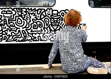 Tenterden, Kent, Royaume-Uni. 26 juillet 2024. L'artiste de renommée internationale Mr Doodle (Sam Cox) crée le premier train Doodle au monde, couvrant un wagon de 64 pieds avec ses griffes signature - pour marquer le 50e anniversaire du chemin de fer Kent et East Sussex, à sa base à la gare de Tenterden dans sa ville natale. Crédit : Phil Robinson/Alamy Live News Banque D'Images