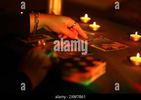 KIEV, UKRAINE - 10 JUILLET 2024 lecteur de tarot cueillant des cartes de tarot. Chandelles dans une pièce sombre. Lecture de tarot et prévision de gros plan sur le lecteur de tarot ou le caissier Banque D'Images