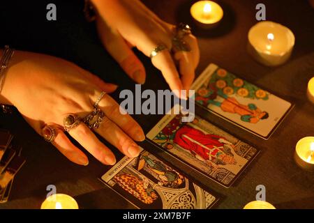 KIEV, UKRAINE - 10 JUILLET 2024 lecteur de tarot cueillant des cartes de tarot. Chandelles dans une pièce sombre. Lecture de tarot et prévision de gros plan sur le lecteur de tarot ou le caissier Banque D'Images