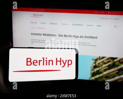 Personne tenant le téléphone portable avec le logo de la société bancaire allemande de crédit hypothécaire Berlin Hyp AG devant la page Web de l'entreprise. Concentrez-vous sur l'affichage du téléphone. Banque D'Images