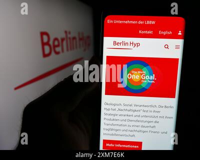 Personne tenant le téléphone portable avec la page Web de la société bancaire allemande de crédit hypothécaire Berlin Hyp AG devant le logo. Concentrez-vous sur le centre de l'écran du téléphone. Banque D'Images