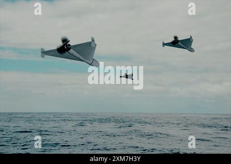 attaque de groupe de drones noirs de kamikazes modernes volant sur fond de ciel bleu et de nuages Banque D'Images