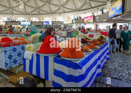 Scène de marché intérieur dynamique au bazar Eski Juva à Tachkent Ouzbékistan avec des femmes vendant des piles de salades fraîches colorées et des légumes marinés Banque D'Images