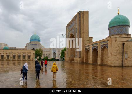 Touristes marchant sur une cour humide au complexe Hazrati Imam à Tachkent, Ouzbékistan Banque D'Images