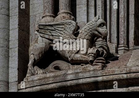 L'un des deux créatures mythologiques ailées avec des becs accrochés flanquant la fenêtre est de l'abside romane de la cathédrale de trente, en Italie, le Duomo di San Viglio. Banque D'Images