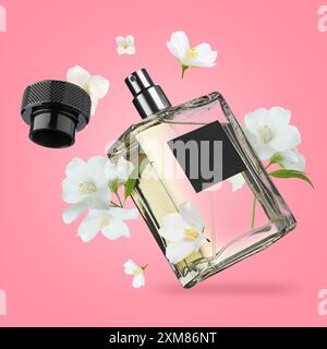 Bouteille de parfum floral et fleurs de jasmin dans l'air sur fond rose Banque D'Images