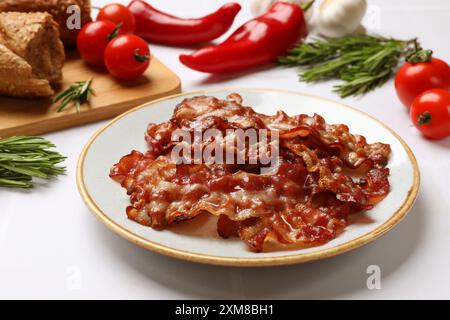 Tranches de bacon frit savoureux, tomates, différentes épices et pain sur table blanche Banque D'Images